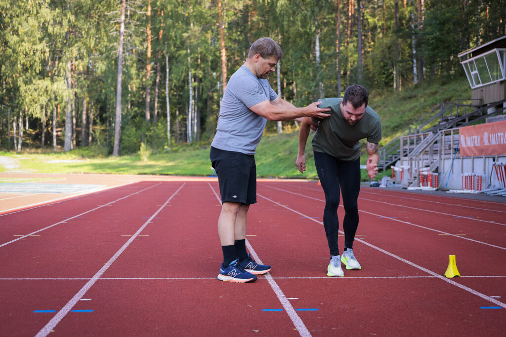 Tero Pusa valmentamassa urheilijaa juoksuun urheilukentällä